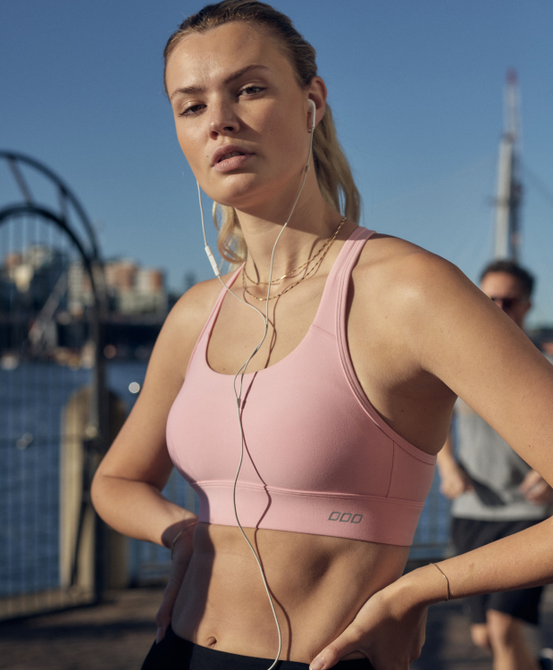 two models wearing sports bras and leggings, with one model clipping the back of the sports bra up